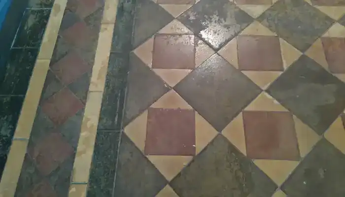 Close-up of worn historic Minton clay tile surface holding ingrained residue
