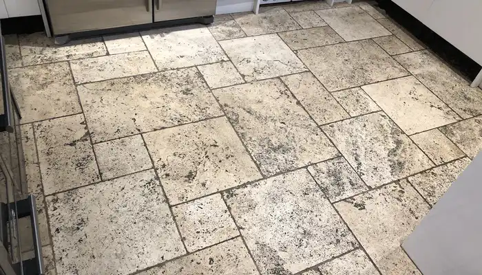 Travertine floor showing darkened patches, worn finish, and uneven surface tone