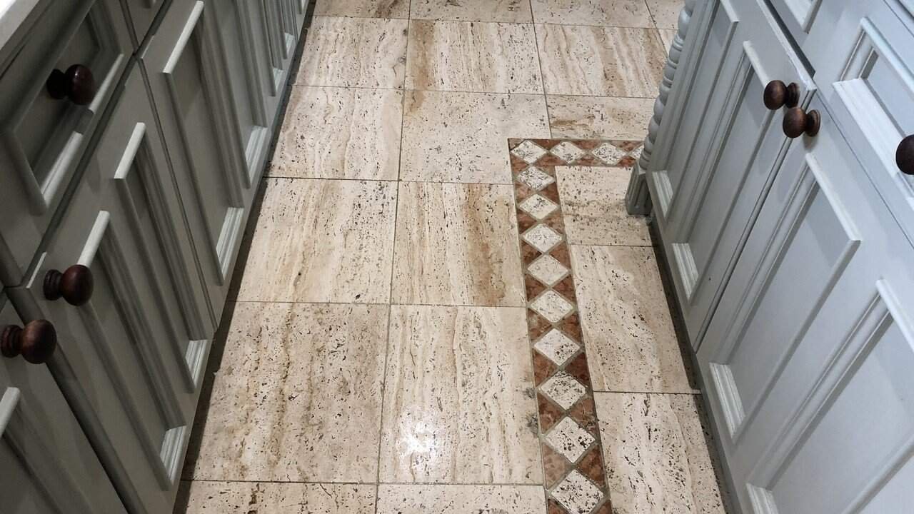 Worn travertine kitchen floor showing dull traffic areas and natural colour variation